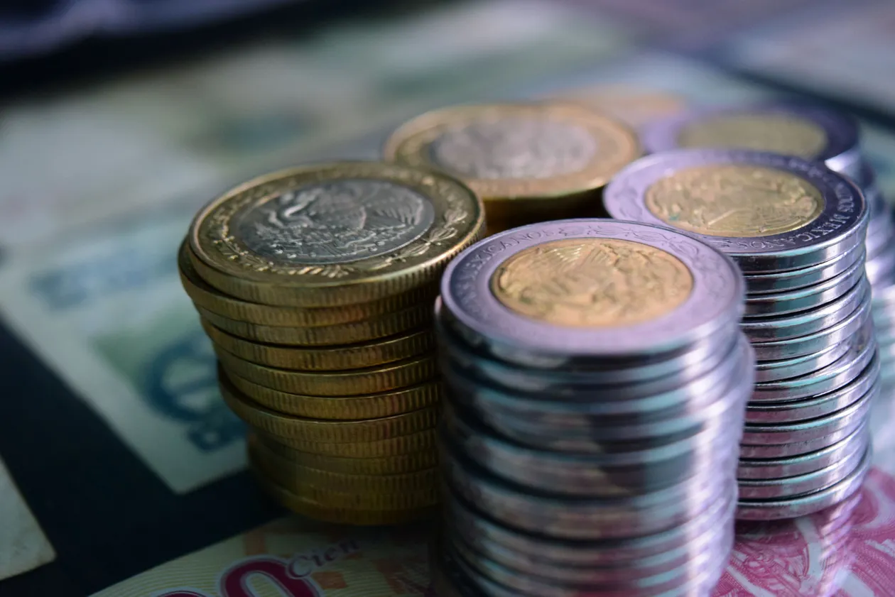 Stacks of silver and gold coins arranged on top of banknotes in close-up view