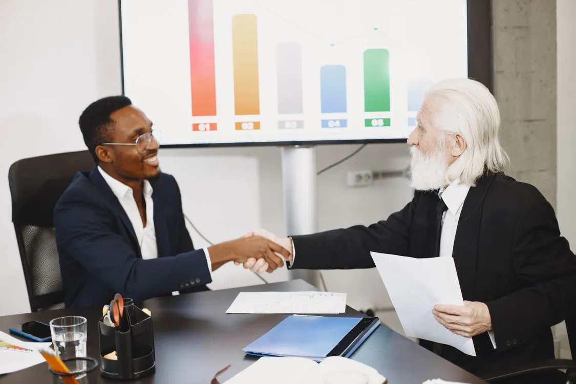 Businessmen shaking hands during a meeting, representing additional business capital