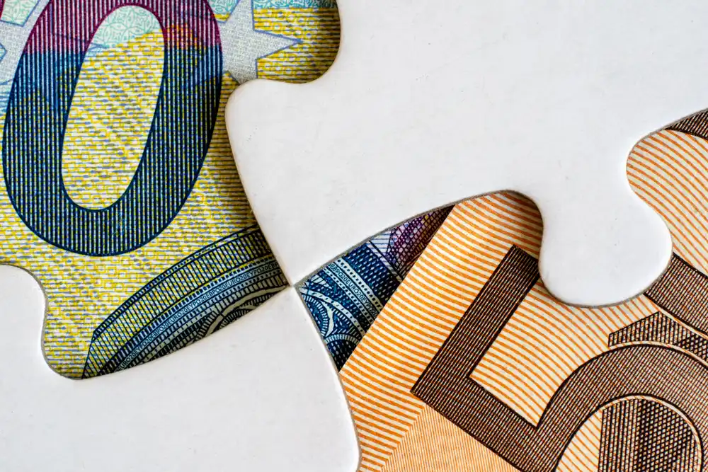 Close-up of two banknote pieces cut like jigsaw puzzle pieces fitting together