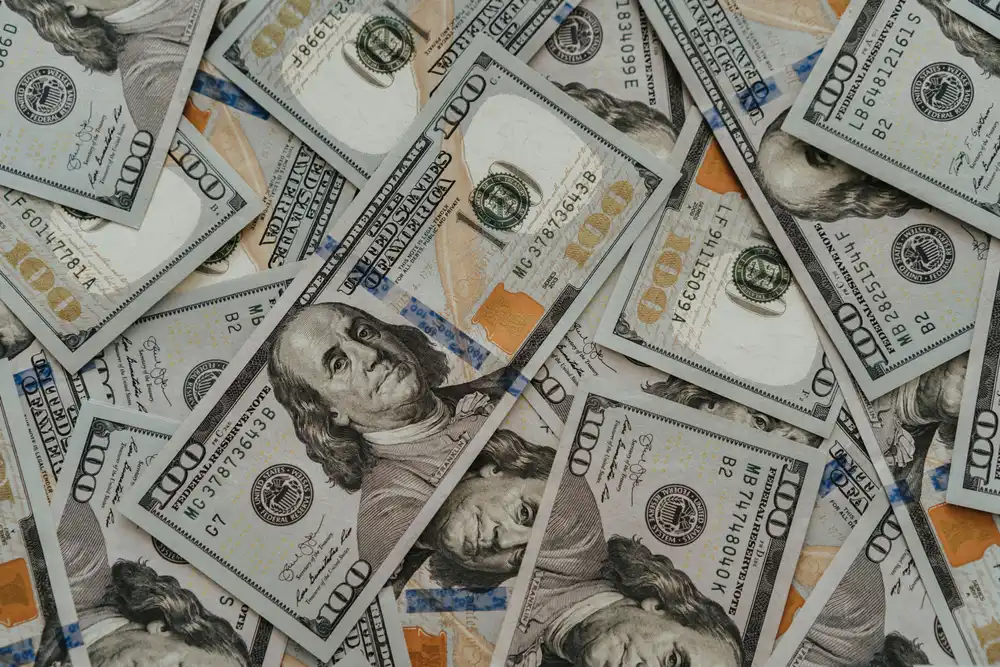 Close-up of scattered U.S. one-hundred-dollar bills covering the frame