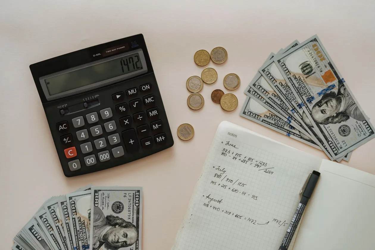 A black calculator beside coins and a notebook for budget planning