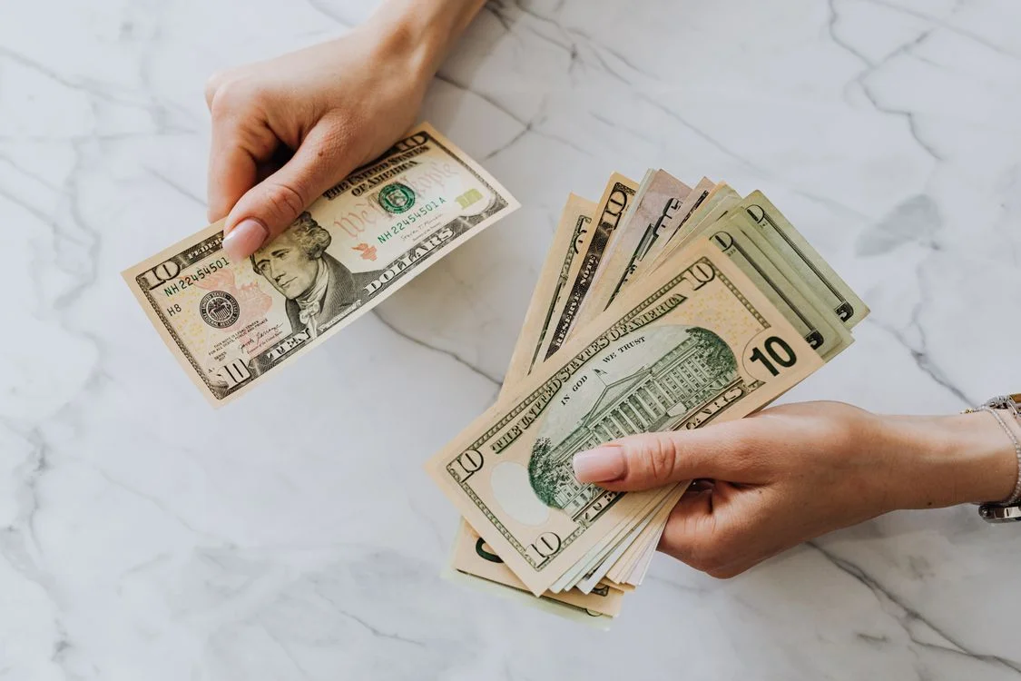 Hands holding US dollar bills — illustrating revenue-based financing capital injection