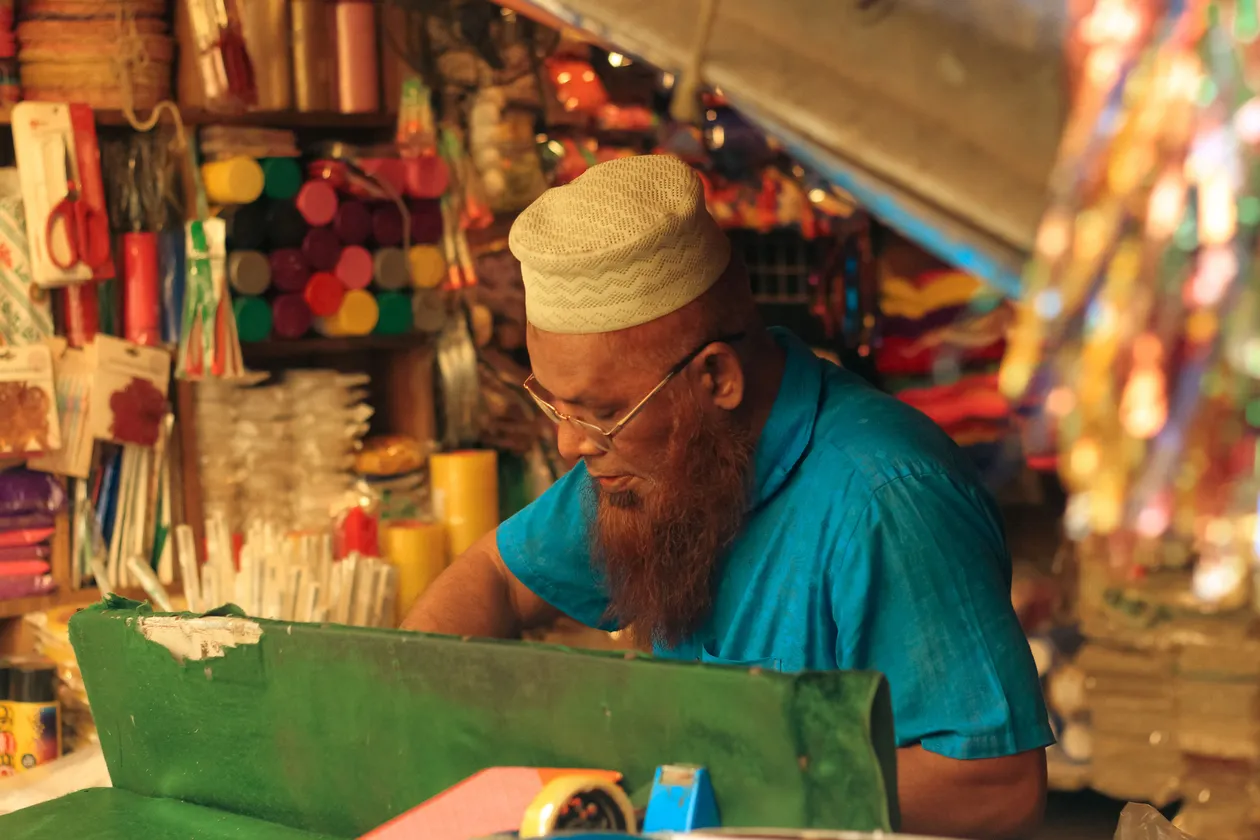 A man working at a colorful market stall in Dhaka, Bangladesh