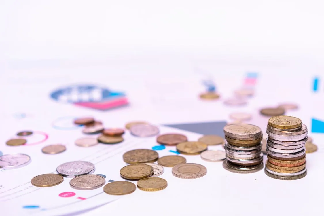 Stacked coins on financial documents, representing financing costs and payment obligations